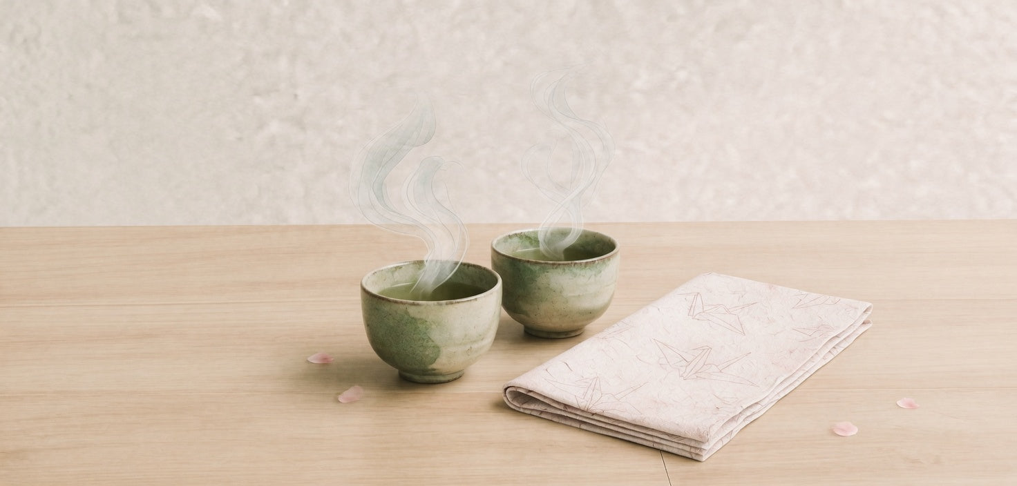 Two tea cups side by side on pale wood.