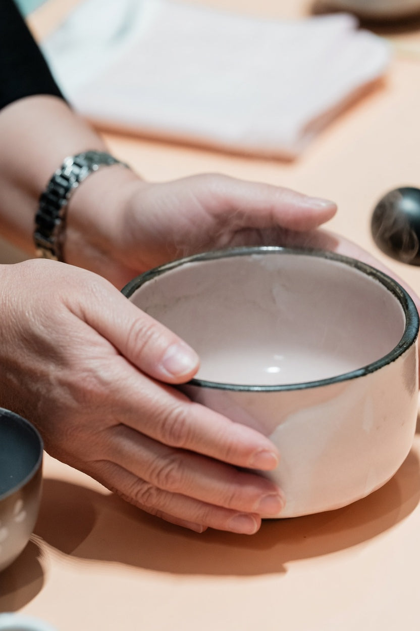 Hands warming a ceramic tea bowl.