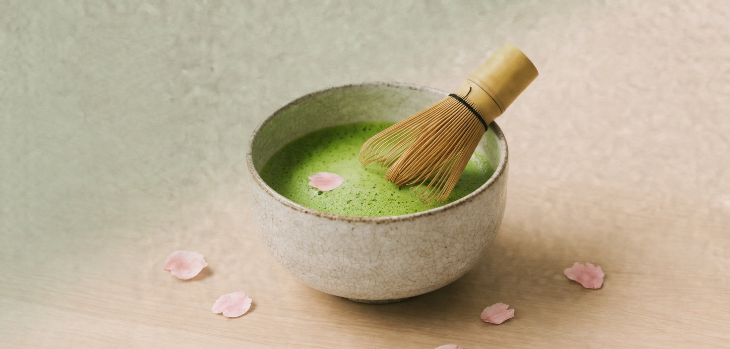 A bowl of whisked matcha on pale wood.